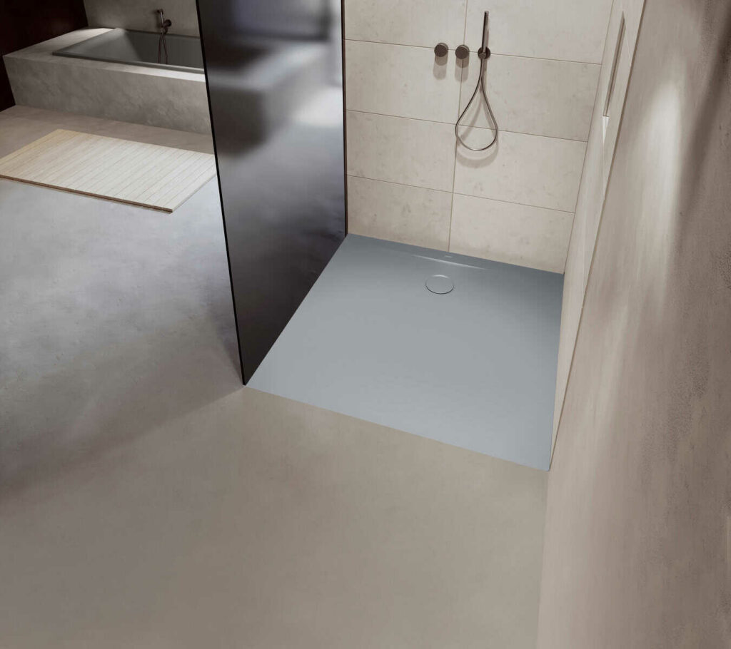 Ambiente de sala de baño con plato de ducha ocre, mampara, grifería de ducha y alicatado y pavimentado beige