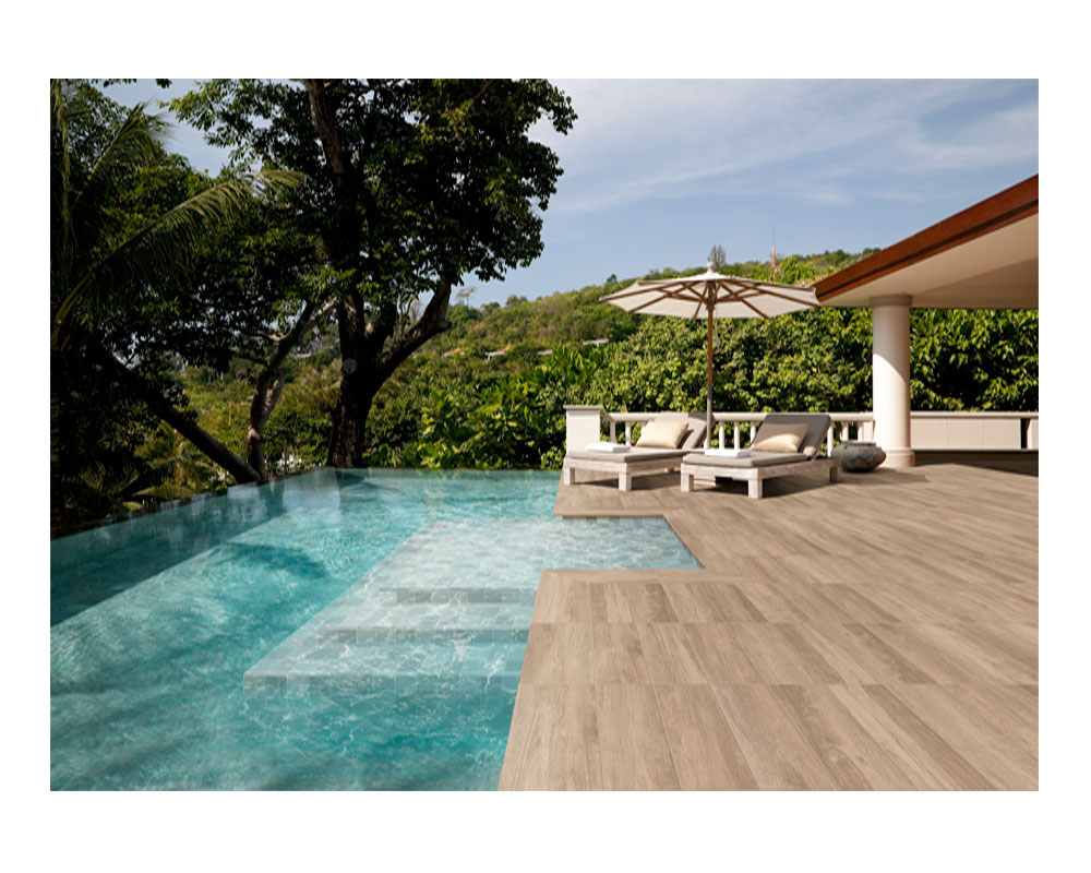 Zona de piscina exterior pavimentada en madera porcelánica.