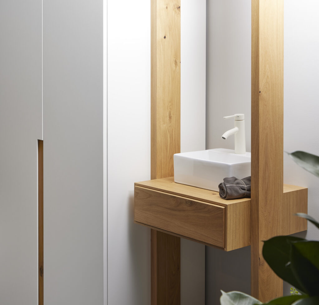 Grifería blanca para baño pequeño en lavabos sobre encimera de madera de pino